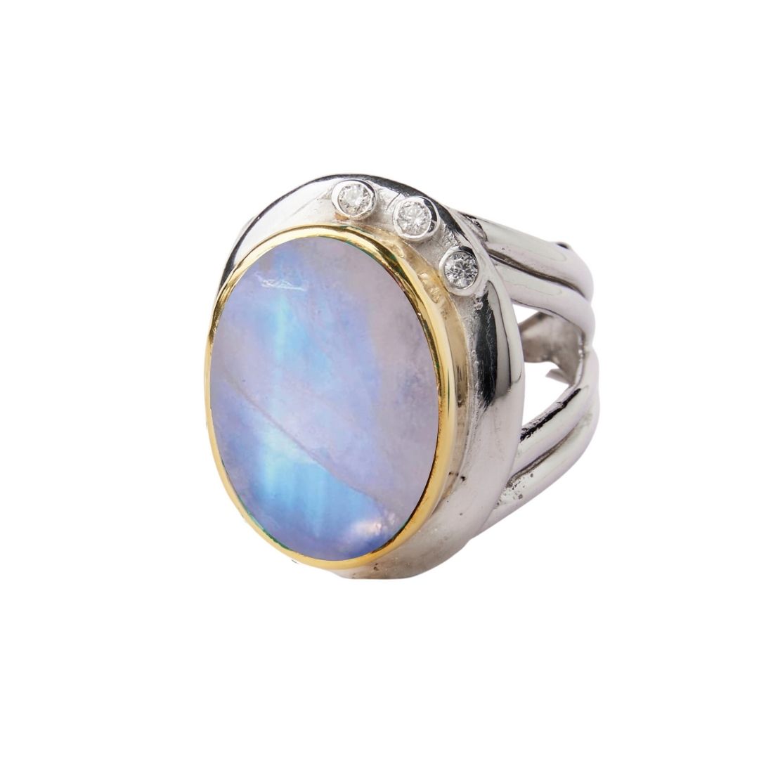 The Eyetelia Ring by Gallardo & Blaine Designs features a large oval blue gemstone set in gold vermeil sterling silver, accented with three small round diamonds on one side.